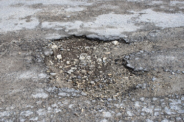A pothole is a damaged surface of a rural road. Pits and potholes on the road. The dilapidated...