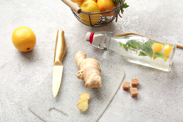 Glass bottle of lemonade with lemons, mint and ginger on grunge grey background