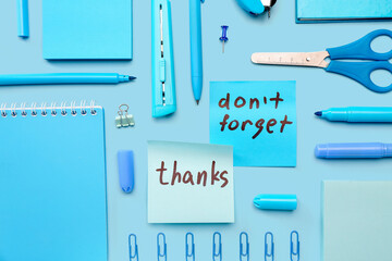 Sticky notes with word THANKS, text DON'T FORGET and stationery on blue background