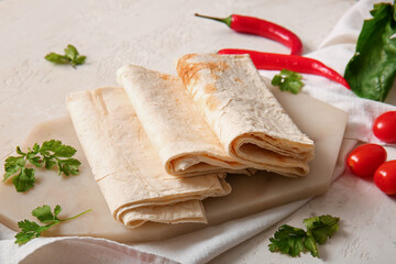 Board with fresh lavash on light background