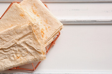 Grid with fresh lavash on white wooden background