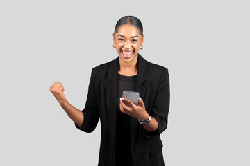 Joyful African American businesswoman in a black blazer showing a triumphant gesture