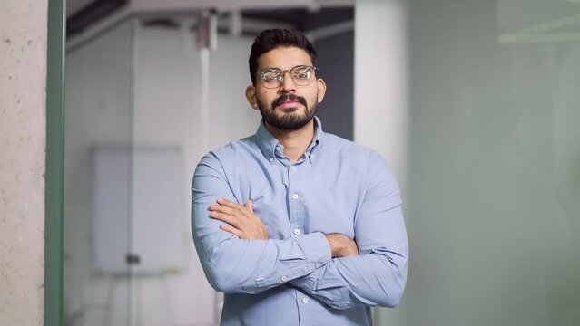 Portrait of a happy successful bearded businessman in a shirt standing with crossed arms in a business office. Confident smiling male owner posing looking at the camera. Head shot of an entrepreneur