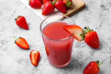 Glass of tasty strawberry juice on grey table