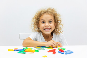 Little girl playing kids constructor, building house from bricks, blocks by assembly instructions....