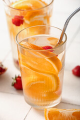Glasses of infused water with orange slices on white tile table