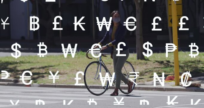 Animation of global currency symbols over asian woman in face mask wheeling bike in street