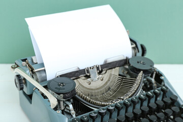 Vintage typewriter on white wooden table near turquoise wall