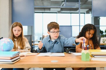 Focused multiracial students kids writing down data into notebook while sitting at table