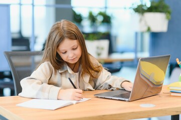 First day at school. Cute and happy little girl children using laptop computer, studying through online e-learning system