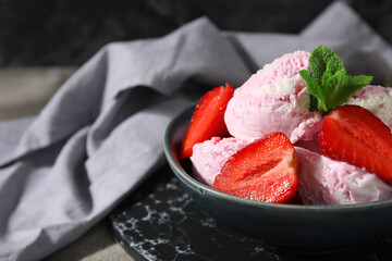 Bowl of strawberry ice cream with berries, mint and tablecloth on table, closeup