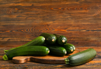 Board with many fresh zucchini on brown wooden background