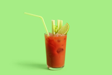 Glass of bloody mary with celery and lime on green background