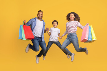 Seasonal Sales Concept. Happy Black Family Of Three Jumping With Shopping Bags