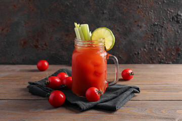 Mason jar of bloody mary with celery and lime on wooden table - obrazy, fototapety, plakaty