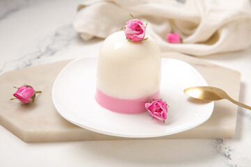 Plate of panna cotta with beautiful pink rose flowers on white table