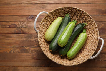 Wicker basket with fresh green zucchini on wooden background