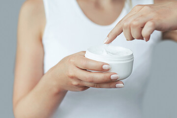 Closeup shot of woman hands holding cream and applying moisturizing hand cream. Beautiful female hands with cream. Hand Skin Care. A woman uses body lotion on your arms. Beauty And Body Care Concept