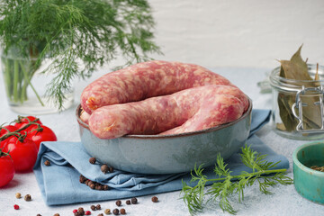 Bowl with raw homemade sausages on light background