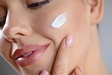 Young beautiful woman applies cream on clean perfect skin. Beauty portrait close-up