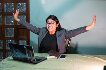 Mujer caucásica con chaqueta gris escribiendo  sentada cerca de la mesa sonriendo