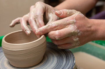 Clay, ceramics or hands in a design workshop working on an artistic cup or mug. The hand of a creative artist or worker making crafts in sculpture