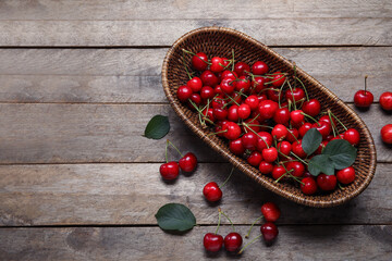 Wicker bowl with sweet cherries on grey wooden background - Powered by Adobe