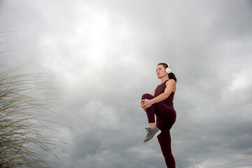 Fototapeta na wymiar Sporty woman doing leg stretching exercises, outside