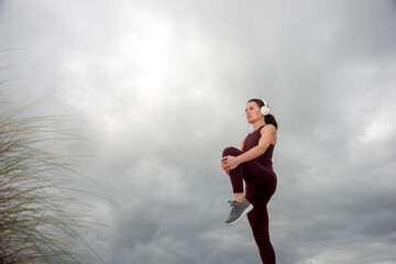 Sporty woman doing leg stretching exercises, outside