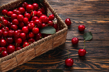 Wicker basket with sweet cherries on wooden background
