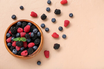 Bowl with different fresh berries on beige background