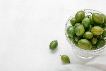 Glass bowl with fresh green gooseberry on white background, closeup