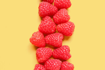 Many fresh raspberries on yellow background