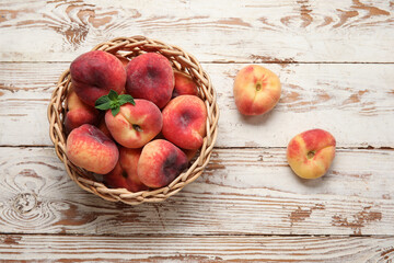 Wicker bowl with sweet fig peaches and mint on white wooden background