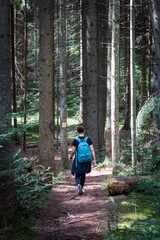 Young women with back pack hiking on a forest trail.