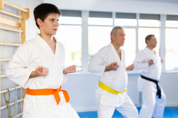 Fighting stance of men of different ages during group karate training. Young guy trains punches
