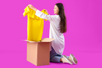 Young Asian woman with new dress and parcel box on purple background
