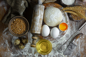 Kneading dough with flour and eggs, with kitchen accessories, on table and old background.