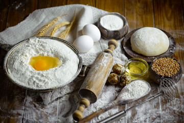Kneading dough with flour and eggs, on an old background