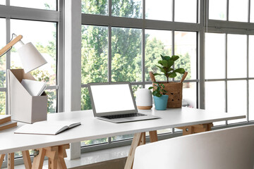 Modern workplace with houseplants near window in office