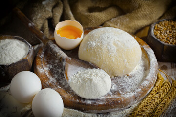 Kneading dough with flour and eggs, on an old background