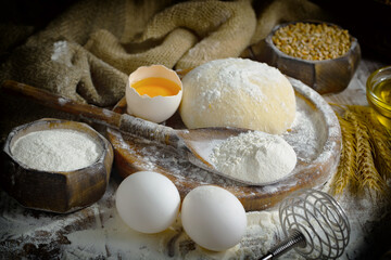 The process of kneading dough in the kitchen. Eggs, flour and other ingredients on the kitchen table in a composition.