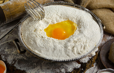 Kneading dough with flour and eggs, on an old background