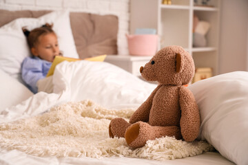 Cute little girl reading book in bedroom