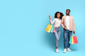 Black couple shopping with colorful bags on blue background