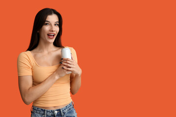 Beautiful young woman with can of cold beer on orange background