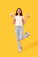 Happy young woman with french fries on yellow background