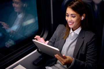 Young happy businesswoman surfing the net on touchpad in train. - obrazy, fototapety, plakaty