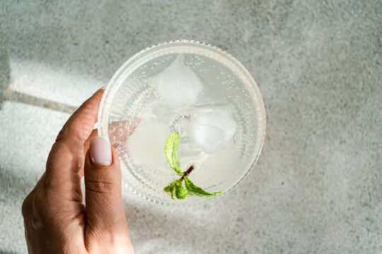 Refreshing drink with lime and mint in a glass held by hand