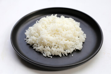 Cooked rice in black plate on dark background.